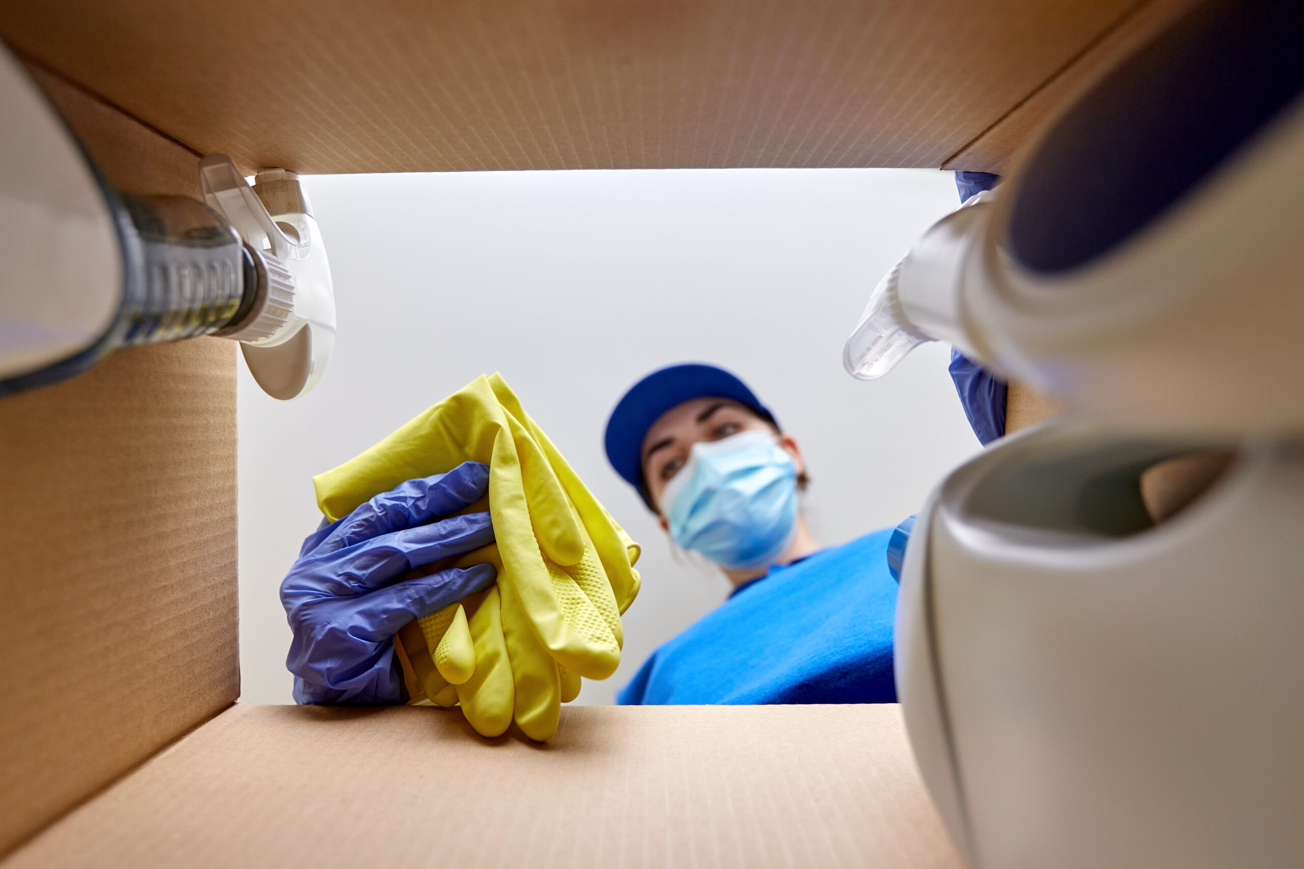 woman in mask packing cleaning supplies in box